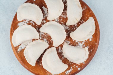 Taze şekilli hamur köfteleri unu ahşap bir tahtanın üzerinde yemek pişirmeyi bekliyor..