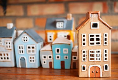 Çeşitli renklerde narin seramik evler ahşap bir yüzeyde tuğlalarla sergileniyordu..