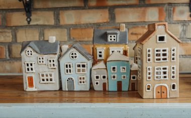 Renkli seramik evler tuğla bir duvara karşı kırsal bir ahşap masada sergilenir..