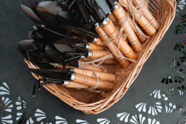 Bir sepetin içindeki ahşap saplı çeşitli bahçe aletleri..