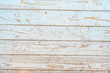 Yıpranmış ahşap kalaslar açık mavi bir renk ve düzensiz boya sıçramaları gösteriyor..