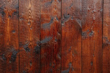 Yıpranmış tahtaların yakın plan çekimleri zengin dokuları ve koyu renkleri vurguluyor