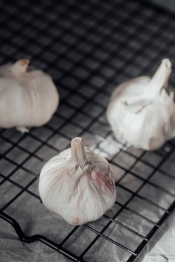 Sarımsak soğanları tel askıda kuruyor, beyaz derilerini ve köklerini sergiliyorlar..