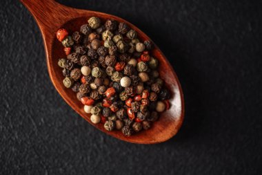 Tahta bir kaşıkta sergilenen çok renkli biber koleksiyonu..