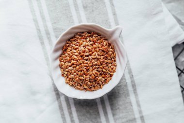 Taze hasat edilmiş keten tohumları mutfak masasındaki bir kaseye güzelce yerleştirilmiş..