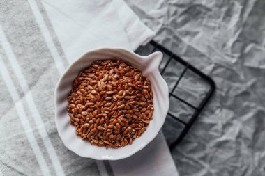 Keten tohumu, beyaz bir kâsede mutfak bezinin üstünde sergilenir..
