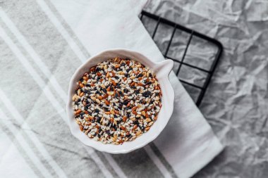 Çeşitli tohumlarla dolu bir kase dokulu bir mutfak tezgahında kullanıma hazır bekliyor..