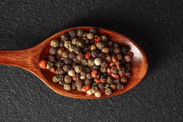 Ahşap bir kaşık, karanlık bir yüzeye karşı çeşitli baharatlar barındırır..