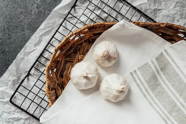 Üç sarımsaklı karanfil, mutfak tezgahında dokuma sepetinde yan yana oturur..