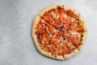 Taze pişmiş pizza üzerine pepperonili ve taze domatesli bir altın kabuk içerir..