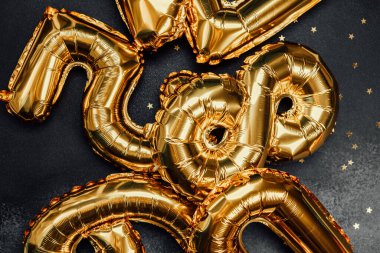 Sayı şeklinde altın balonlar, şenlikli bir olay için karanlık bir arkaplan süslüyor..