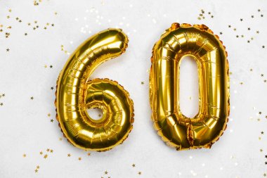Altmış numara şeklinde altın balonlar parlak konfetilerle çevrilidir..