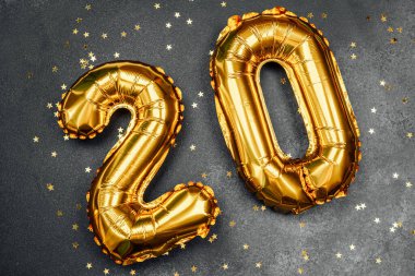 Altın yıldızlarla çevrili yirmi numara şeklinde parlak altın balonlar.