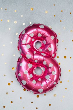 Parlak bir zemin üzerinde gümüş kalpler olan parlak pembe sekiz numaralı balon..