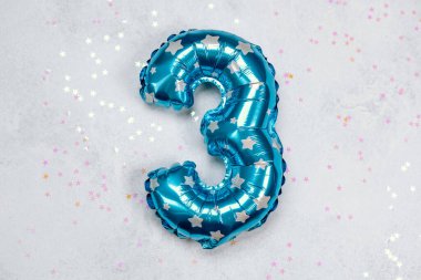 Parlak mavi bir balon. Üç numara şeklinde. Etrafı renkli yıldızlarla çevrili..