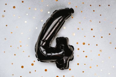 Dört numaralı siyah bir balon ışıldayan altın bir arkaplanda duruyor..