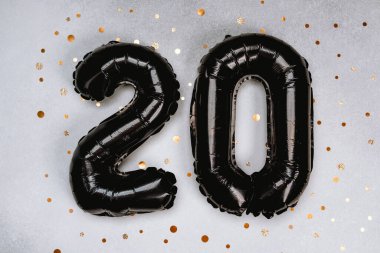 Altın konfetiyle süslenmiş ışıl ışıl arka planda siyah balonlar..