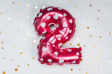 Beyaz kalplerle süslenmiş iki numaralı kırmızı balon gösteriliyor..