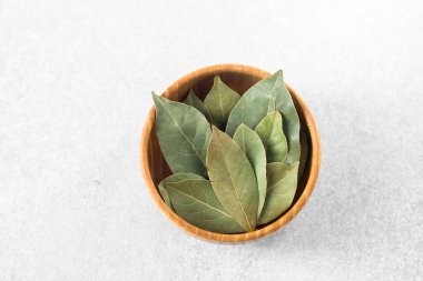 Körfez yaprakları ahşap bir kaseye güzelce yerleştirilir ve zengin yeşil renklerini sergilerler..