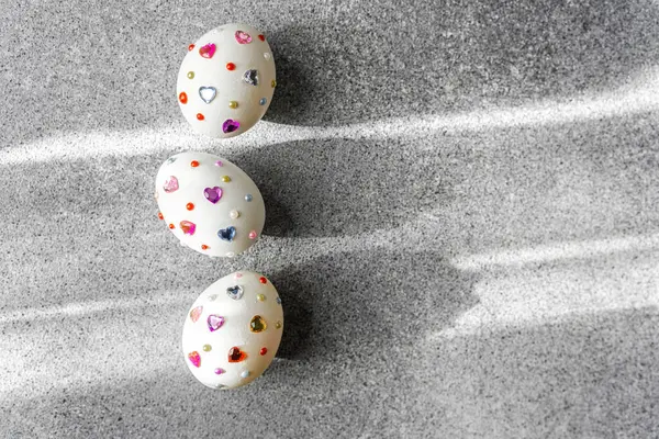 Renkli kalpleri olan güzel dekore edilmiş yumurtalar pürüzsüz gri bir yüzeye yerleştirilmiş.