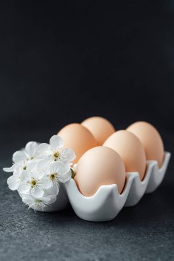 Beyaz çiçekli beyaz bir kutuya yerleştirilmiş beş taze yumurta..