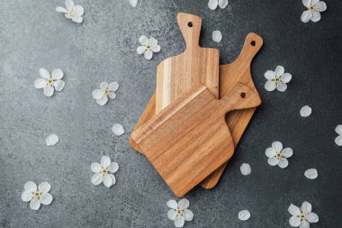 Üç tahta kesme tahtası zarif bir şekilde yumuşak beyaz çiçeklerle yerleştirilir..