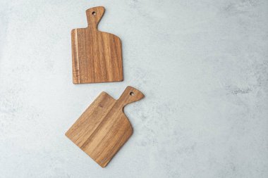 Açık gri bir tezgahın üzerine yerleştirilmiş iki farklı tahta doğrama tahtası dokuyu gösteriyor..