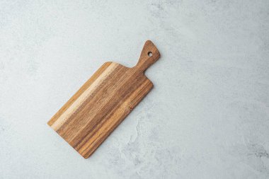 Tahta doğrama tahtası pürüzsüz, açık gri bir tezgahta durur..