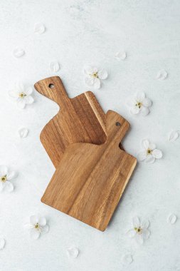 İki tahta kesme tahtası, ince yapraklarla çevrili hafif bir yüzeyde otururlar..