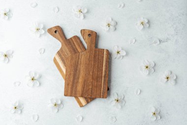 İki tahta kesme tahtası beyaz çiçeklerle çevrili bir arka plana yerleştirilmiş..