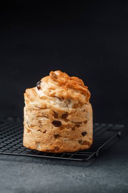 Bir somun tatlı ekmek, karanlık bir mutfak ortamında tel askıda soğuyor..