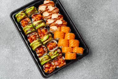 Somon, avokado ve gri arka planda özel soslu suşi..