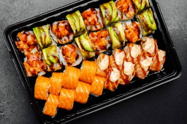 Renkli suşi tabağı canlı rulo ve güzel süslenmiş taze somon balığı sergiler..