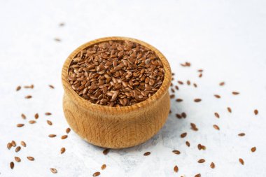 Keten tohumları ahşap bir kaseden hafif bir yüzeye dökülür..