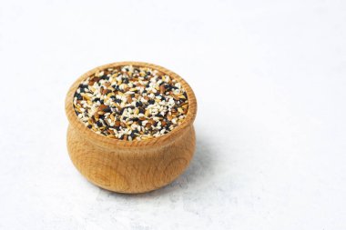 Temiz beyaz bir yüzey üzerinde çeşitli tohumlarla dolu ahşap bir kase..