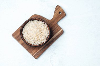 Pişmemiş pirinçle dolu bir kase ahşap bir kesme tahtasına konur..