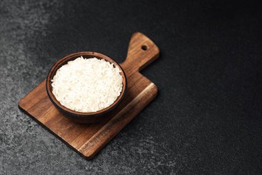 Beyaz pirinçle dolu bir kase mutfak ortamında bir kesme tahtasının üzerinde oturur..