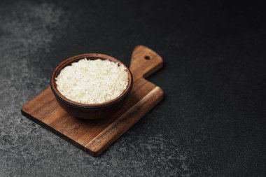 Koyu yüzeyi olan tahta bir tahtanın üzerine yerleştirilmiş beyaz pirinç..