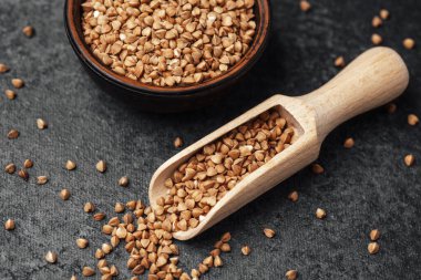 Karabuğday taneleri, karanlık bir tezgahın üzerindeki bir kasenin yanındaki tahta kepçeden dökülür..