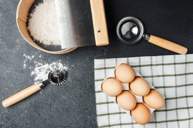 Koyu bir mutfak yüzeyinde gösterilen pişirme malzemeleri ve araçları.