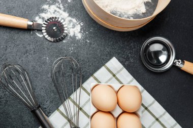 Yumurtalar mutfak havlusunda, alet edevat ve unun yanında, pişirilmeye hazır..