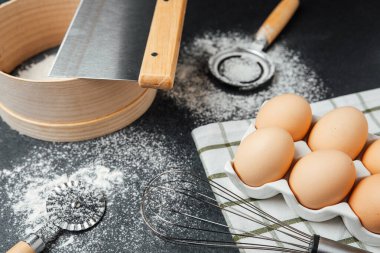 Taze yumurtalar bir kabın içinde, mutfak tezgahındaki un ve fırın aletlerinin yanında otururlar..