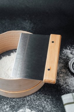 Hamur kazıyıcı ve un da dahil olmak üzere temel malzemeler tezgahın üzerine dizilmiştir..