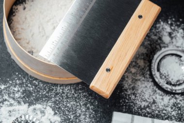 Kenar kazıyıcı bir kase un üzerinde dinlenirken malzemeleri yakınlarda pişiriyor..