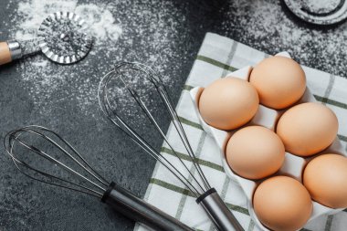 Altı yumurta çırpılmış çırpılmış ve un etrafa saçılmış bir kumaş üzerinde düzgünce sıralanır..