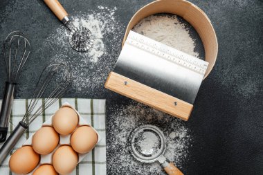 Yumurta ve un, mutfak aletleriyle birlikte tezgahın üstünde düzgünce sergilenir..