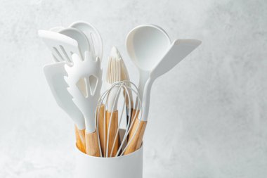 Beyaz mutfak aletleri arasında spatulalar ve bir tutucu içinde çırpı, vitrin organizasyonu.