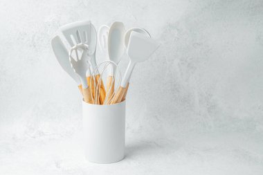 Çeşitli mutfak gereçleri arka planda beyaz bir konteynıra yerleştirilmiş..