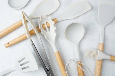 Spatulalar, maşalar ve düzgünce yerleştirilmiş fırça da dahil olmak üzere çeşitli mutfak aletleri..