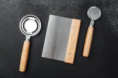 Anahtar mutfak aletleri: hamur kazıyıcı, pasta tekeri, ve tezgahın üzerinde elek.